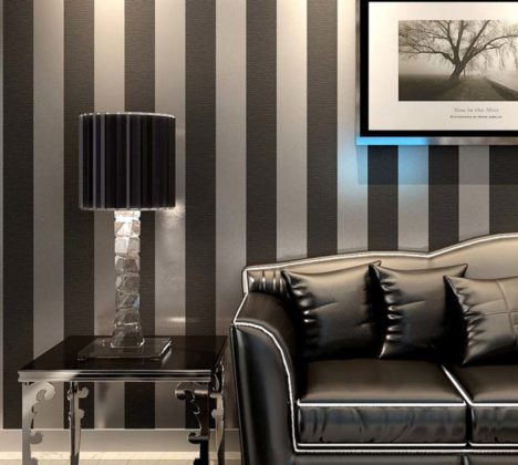 sala decorada com papel de parede e sofá preto