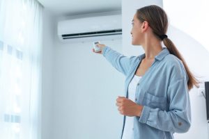 Mulher ligando seu aparelho após entender as diferenças entre Ar-condicionado e climatizador.