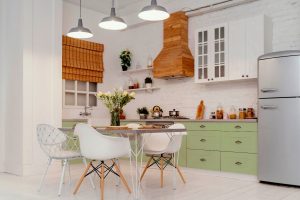 Imagem de cozinha branco com armários verdes e itens decorativos. Feita ao entender como decorar cozinha.