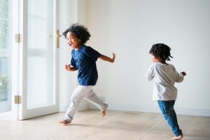 Crianças correndo dentro de casa, em um ambiente com decoração segura para crianças.