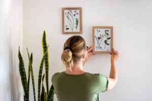 Mulher descobrindo como decorar apartamento alugado utilizando quadros e plantas.