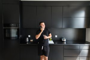 Homem em uma cozinha totalmente preta com armários e eletrodomésticos. 