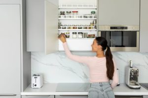 mulher organiza armário após seguir as dicas para decoração de cozinhas pequenas